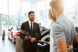 Car Salesmen in dealership with young couple