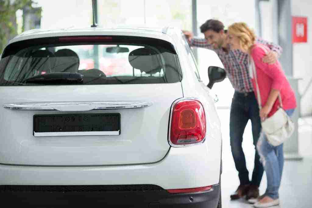 How Can Your Business Generate More Car Loan Leads? 6 Young couple looking at the inside of a new car at a dealership