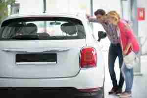 Young couple looking at the inside of a new car at a dealership