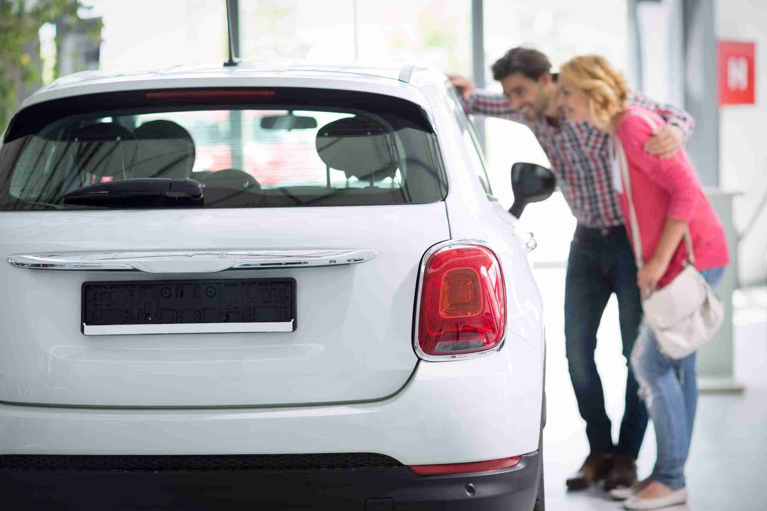 Young couple looking at the inside of a new car at a dealership