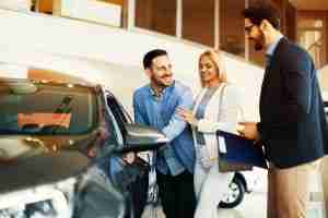 Happy Couple in Car Dealership with Car Salesmen