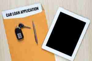Car Loan Application in folder with keys, pen and iPad on top