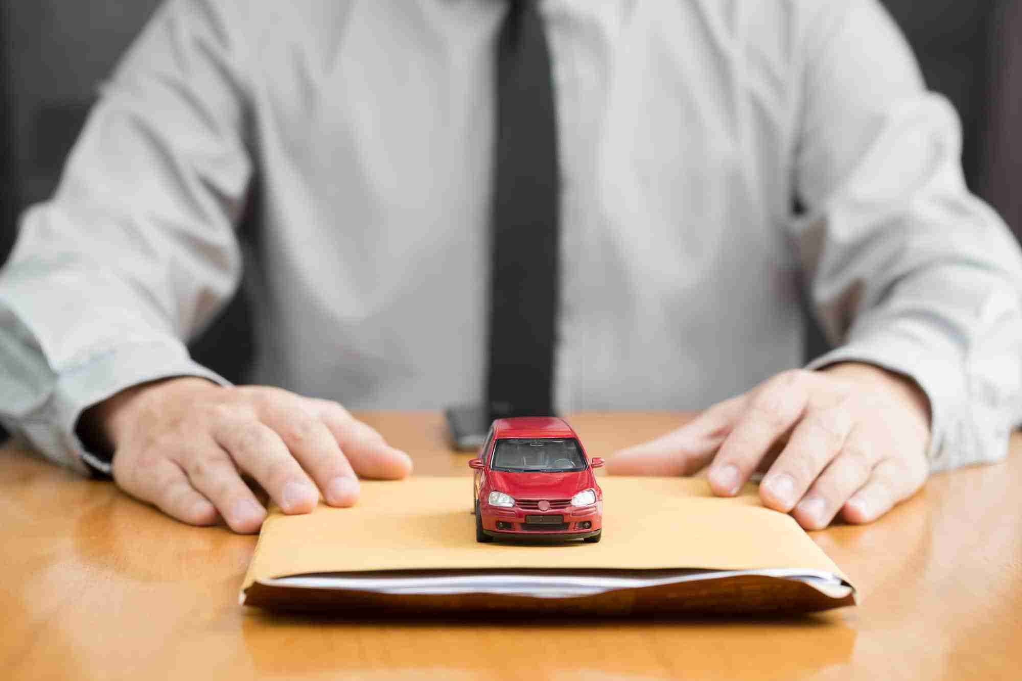 Toy car on top of car salesmen envelope.