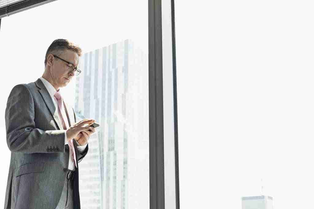 To Text or Not to Text – Is Your Dealership Taking Advantage of Text Communication? 25 Business man standing at the window and texting