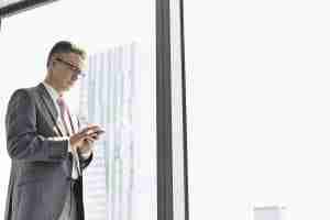 Business man standing at the window and texting