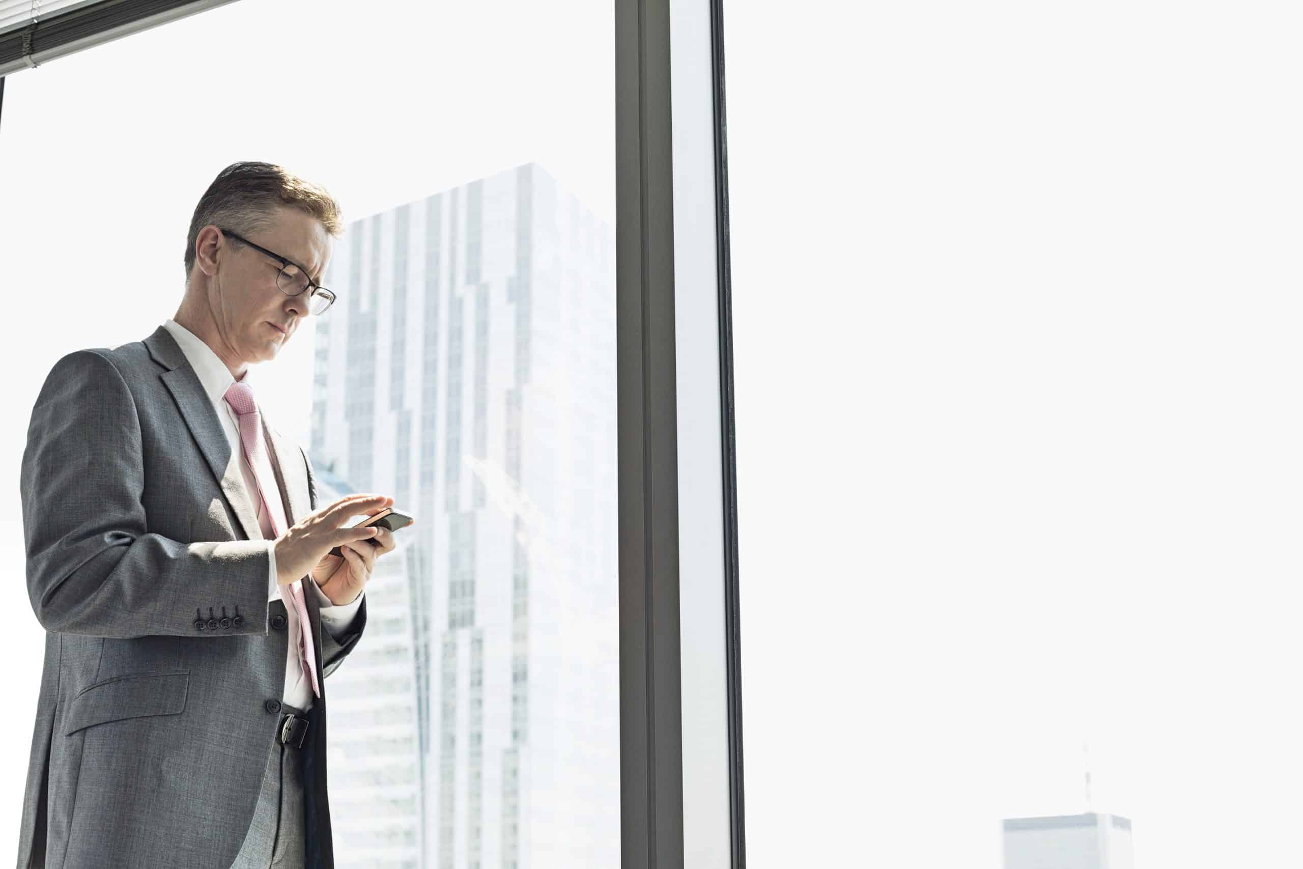 Business man standing at the window and texting