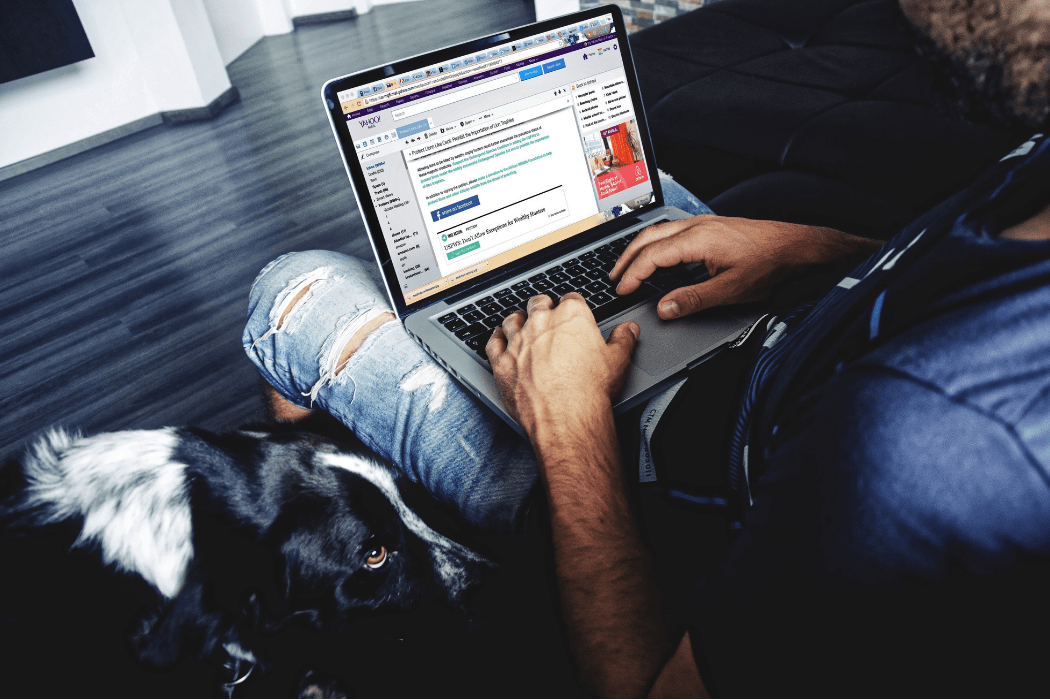Man sitting with dog browsing the internet on his laptop